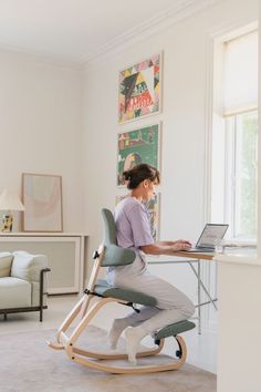 a woman sitting at a desk with a laptop computer on her lap top while using the ergonomic chair