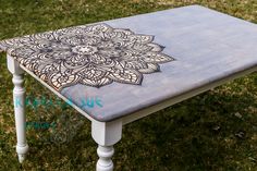 a wooden table with an intricate design painted on it's top in the grass