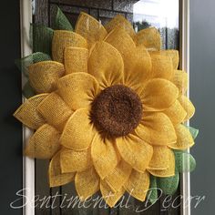 a yellow sunflower is hanging on the front door with burlocks and green leaves