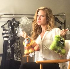 a woman sitting in a chair holding two bags of fruit