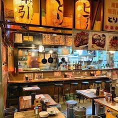 the interior of a restaurant with many tables and stools in front of it, along with posters on the wall