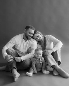 a black and white photo of a man, woman and child sitting on the floor