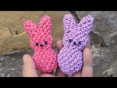 two small crocheted bunnies with eyes on them in the palm of someone's hand