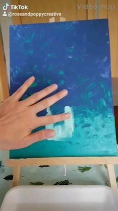 a person's hand is on top of a painting in the process of being painted