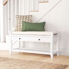 a white bench with a green pillow on it in front of a stair case and rug