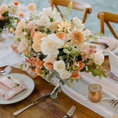 the table is set with pink napkins and white plates, silverware and flowers