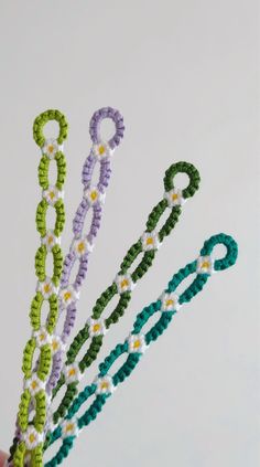 three crocheted beads are being held up in the air