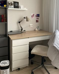 a desk and chair in a room with white curtains on the window sill above it