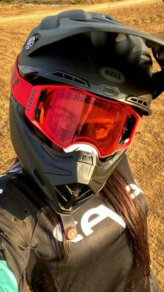 a woman wearing a helmet and goggles on top of a dirt field in the desert