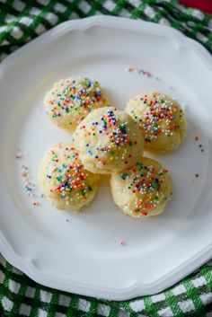 small cookies with sprinkles on a white plate next to a green and white checkered table cloth