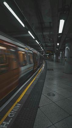 the train is moving through the station with its lights on and it's motion blurry