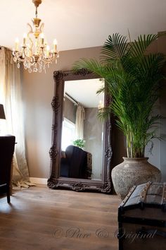 a large mirror sitting on top of a wooden floor next to a chair and table