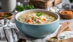 a blue bowl filled with chicken noodle soup on top of a wooden cutting board