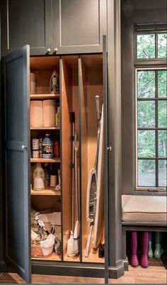 an open cabinet in the corner of a room with lots of clutter and cleaning supplies