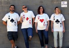 four people wearing matching t - shirts with playing cards on them, standing in front of a brick wall