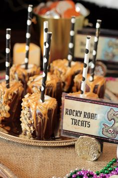 desserts are arranged on a tray with candy sticks in the middle and sign that says rocky road treats