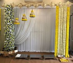 the stage is decorated with yellow flowers and white drapes, hanging from gold chandeliers