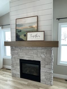 a fireplace with a painting on top of it next to two windows and a window sill