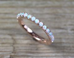 a white opal and diamond ring sitting on top of a wooden table