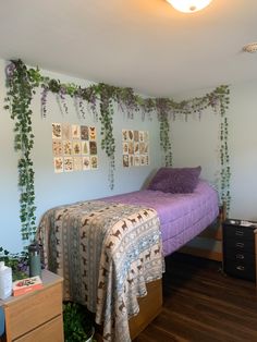 a bed sitting in a bedroom next to a wooden dresser under a plant covered wall