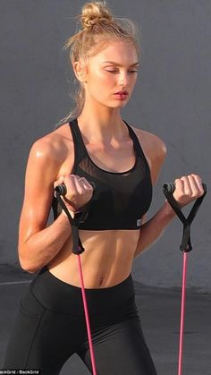 a woman in black sports bra top holding two pink handles