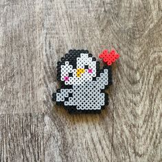 a black and white kitty beaded brooch sitting on top of a wooden table