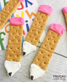 three crackers with marshmallows and pink icing on them sitting next to a card