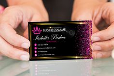 a person holding up a business card with pink glitter on the front and black back