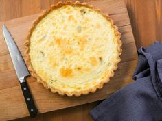 a quiche on a cutting board next to a knife