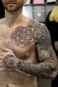 a man with tattoos on his chest and arm is holding something in his other hand