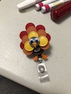 a turkey shaped clip is attached to a white surface next to crayons and markers