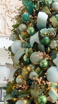 a christmas tree decorated with green and gold ornaments, ribbons and bows on it's branches