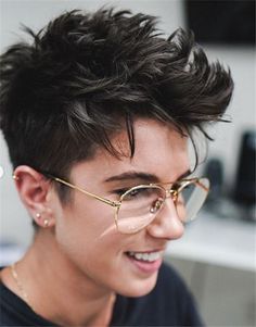 a young man wearing glasses and smiling at the camera with his hair pulled back into a pixie