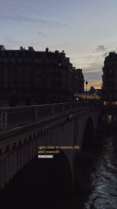 a bridge that is over some water with buildings in the background and a quote on it