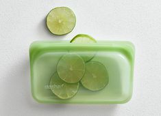 sliced limes in a green plastic container on a white surface