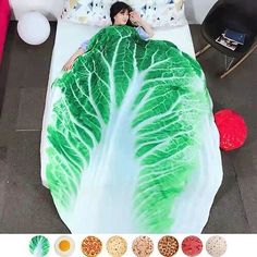 a woman laying in bed with a large green leafy blanket on top of it