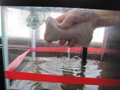 a person is washing their hands with soap in a container that has water and red tape around it