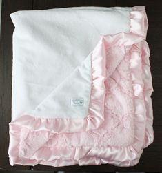 a pink and white blanket laying on top of a wooden table