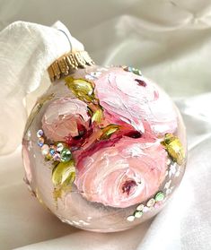 a glass ornament with pink flowers painted on it