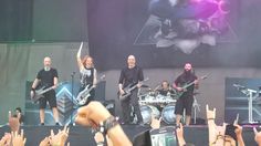 a group of people standing on top of a stage holding up their hands in the air