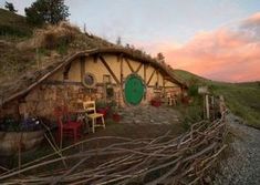 a hobbot house with a green door surrounded by greenery and trees at sunset