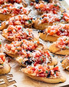 several pieces of bread with tomatoes and cheese on them sitting on a cutting board, ready to be eaten