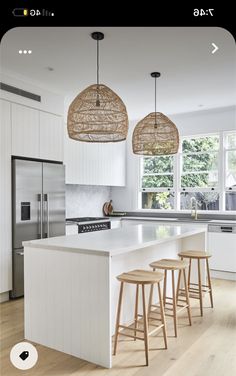 a kitchen with three stools and an island in the middle, surrounded by white cabinets