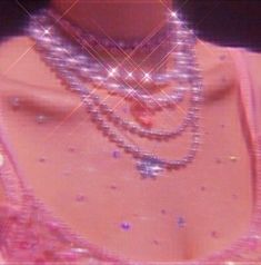 a woman in a pink dress with pearls on her neck and necklaces around her neck