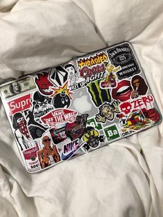 a laptop covered in stickers sitting on top of a bed