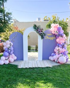 an arch decorated with balloons and flowers for a baby shower