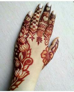 a henna on someone's hand with red and white designs