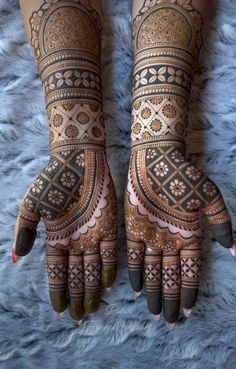 two hands with henna tattoos on them, one is showing the intricate design and the other has geometric designs