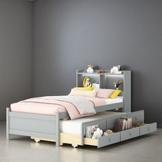 a bed with two drawers underneath it in a gray room next to a white wall