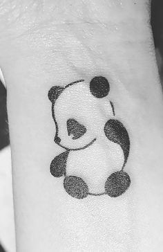 a small panda bear tattoo on the wrist